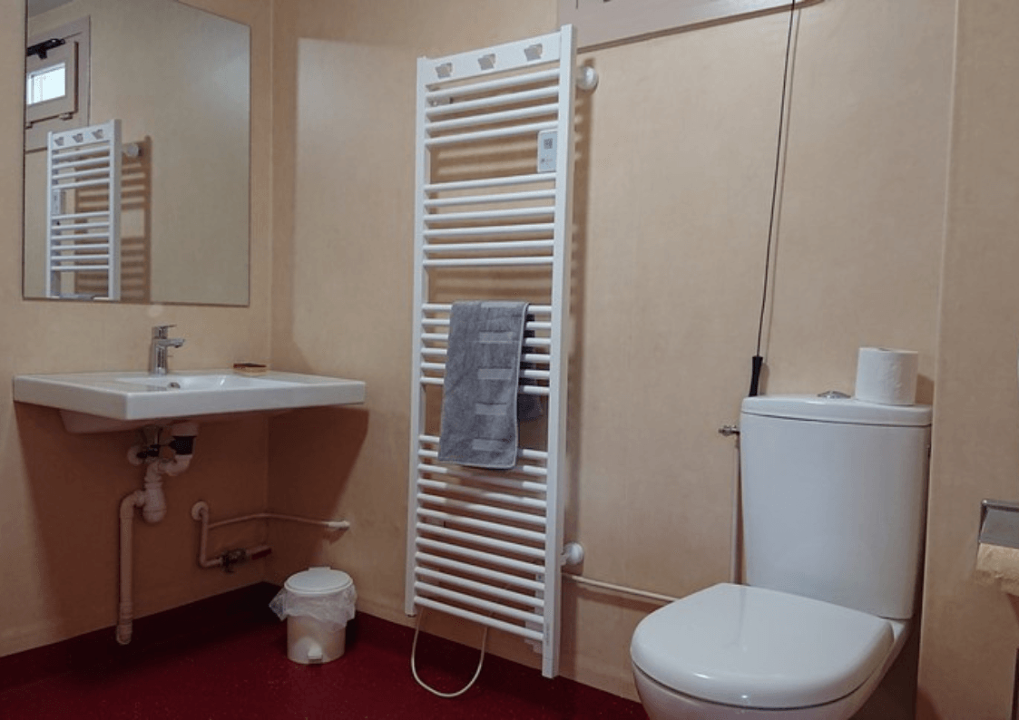 Salle de bain : Salle de bain accessible aux personnes à mobilité réduite avec douche à l'italienne, lavabo et toilettes PMR.
