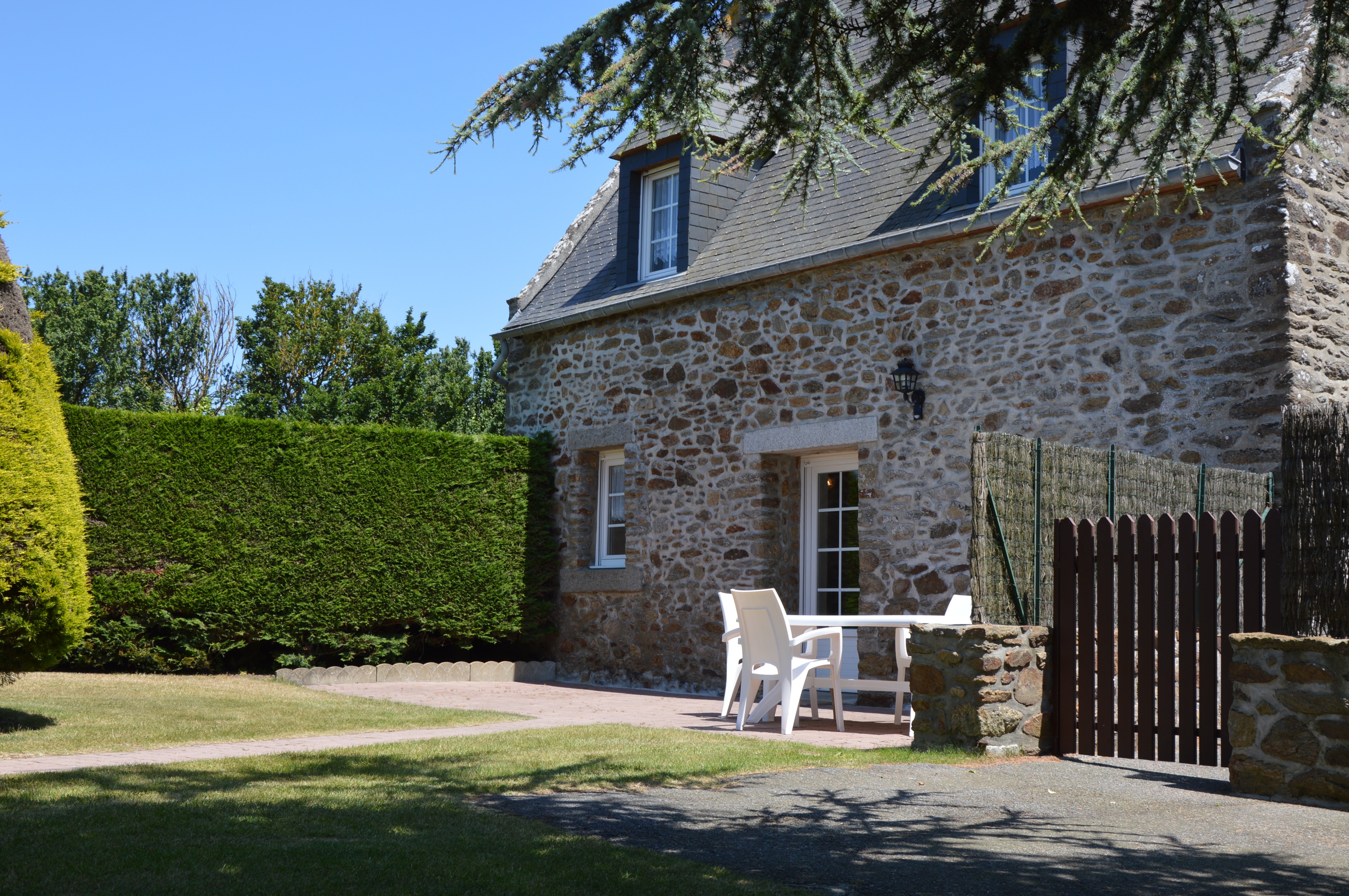 Agréable jardin de 600 m² avec terrasse et salon de jardin, transats, et barbecue.