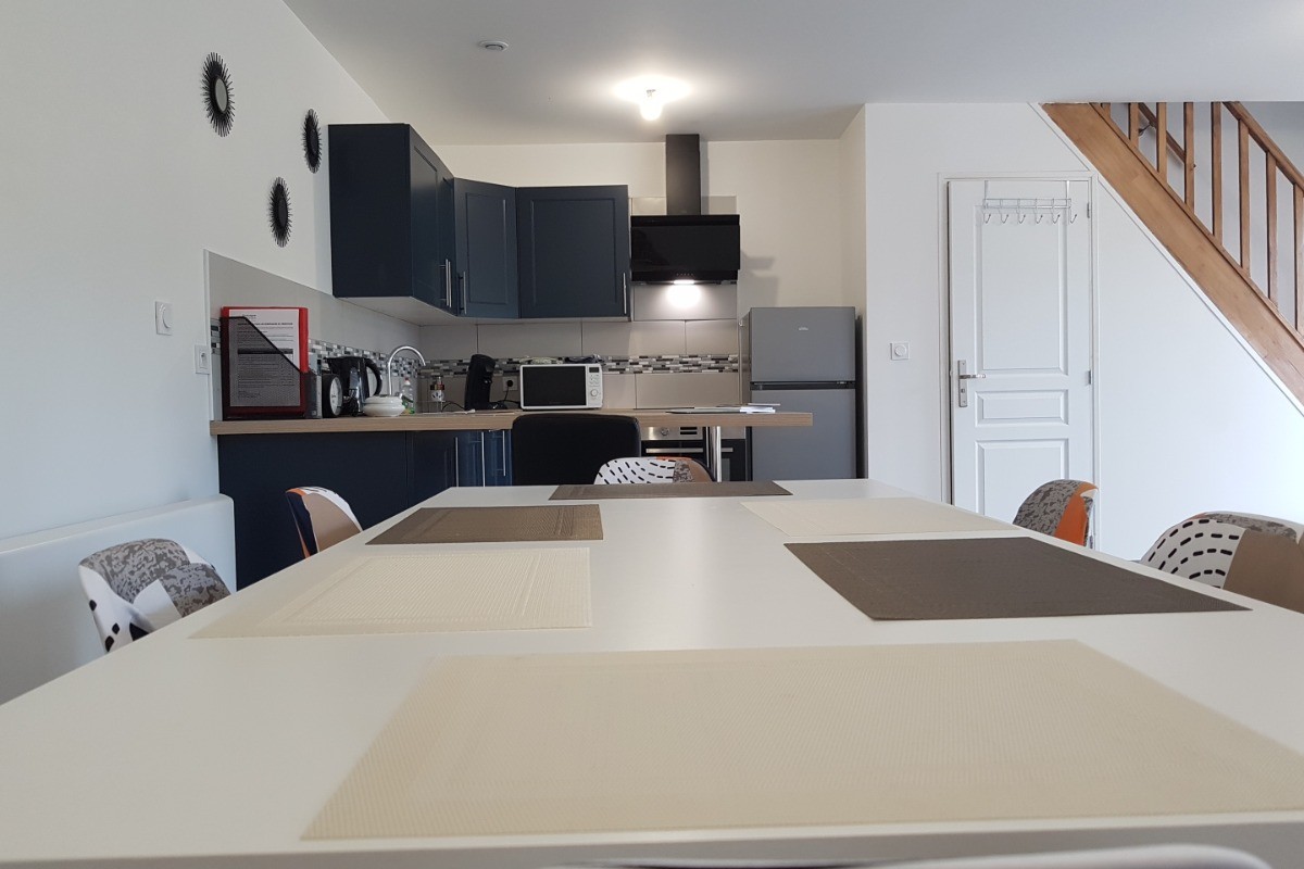 Grande pièce de vie de 32 m² avec coin cuisine toute équipée, coin séjour et coin salon. Accès à la terrasse de plain-pied.