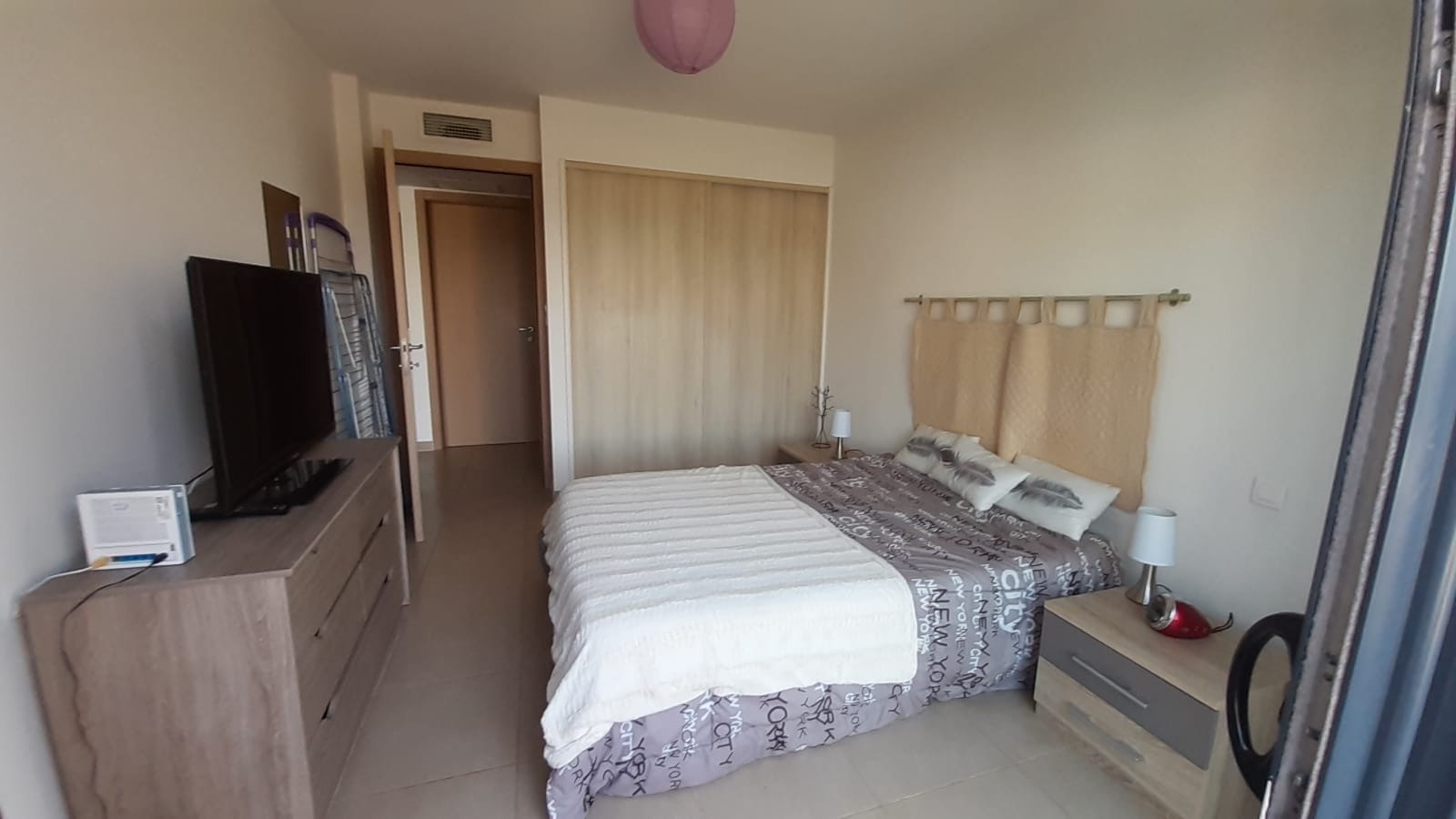 chambre avec commode, TV et grand placard dans le fond