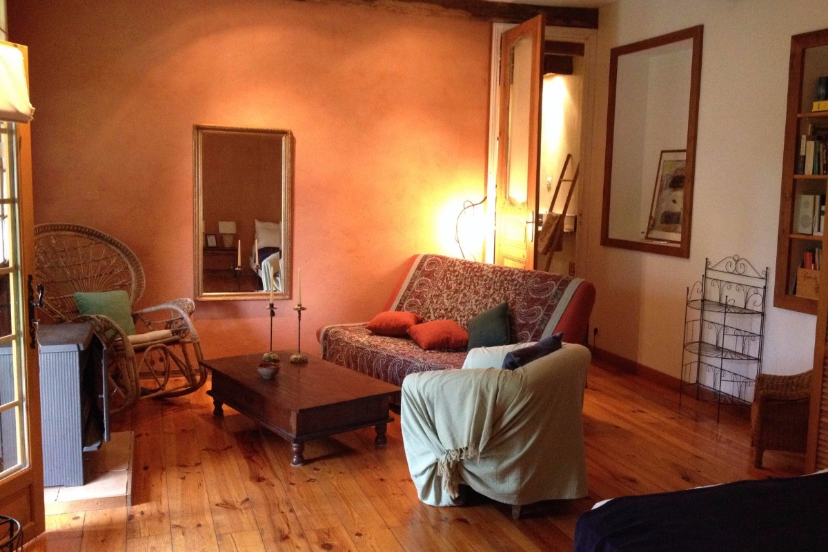 Séjour/chambre du gîte avec poêle à bois, canapé lit et cuisine séparée