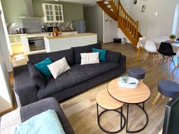 Grande pièce de vie lumineuse avec coin cuisine, coin salon et coin séjour. Accès à la terrasse par la baie vitrée côté séjour.