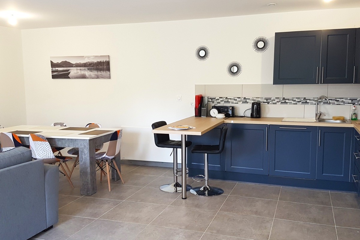 Grande pièce de vie de 32 m² avec coin cuisine toute équipée, coin séjour et coin salon. Accès à la terrasse de plain-pied.
