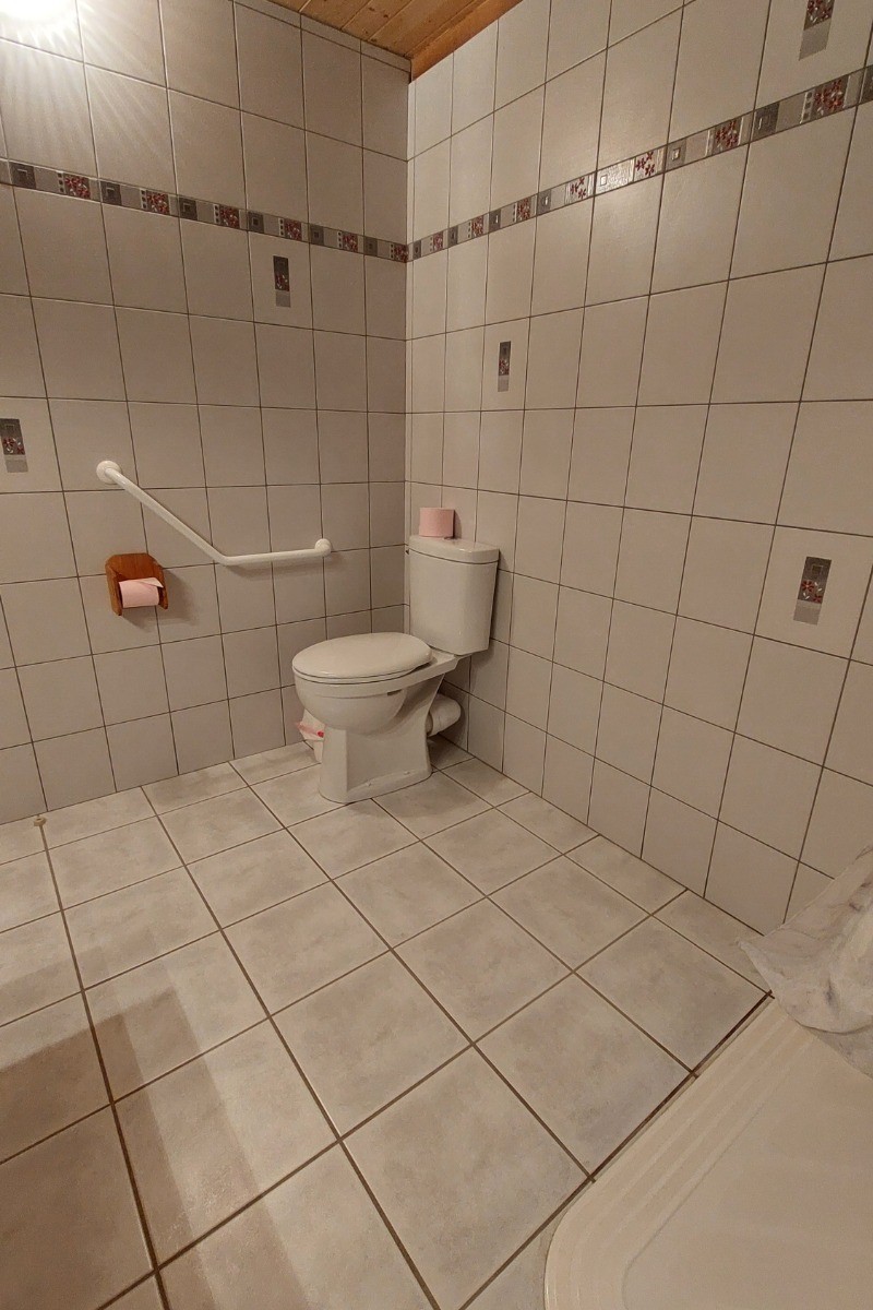 WC accessibles aux personnes en fauteuil roulant dans une chambre d'hôtes PMR, avec barres d'appui.