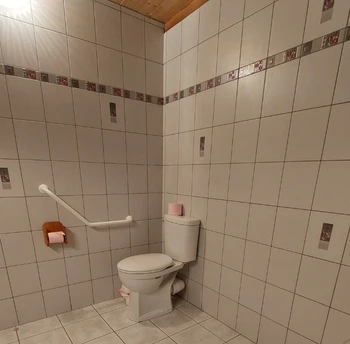WC accessibles aux personnes en fauteuil roulant dans une chambre d'hôtes PMR, avec barres d'appui.