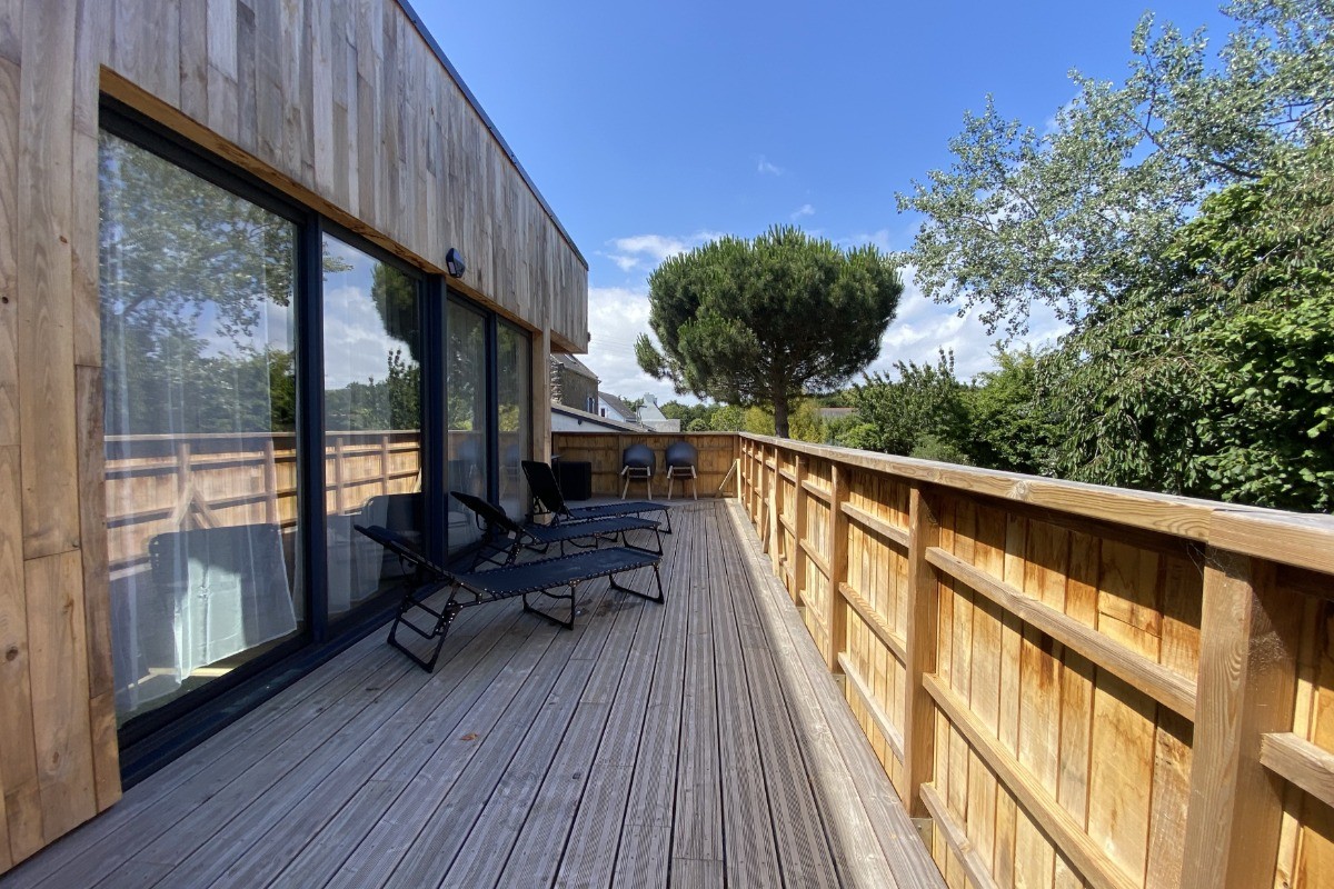 Grande terrasse de plus de 40 mètres carrés avec transats et salon de jardin.