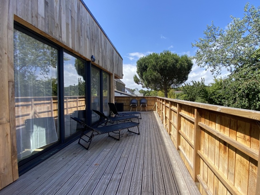 Grande terrasse de plus de 40 mètres carrés avec transats et salon de jardin.