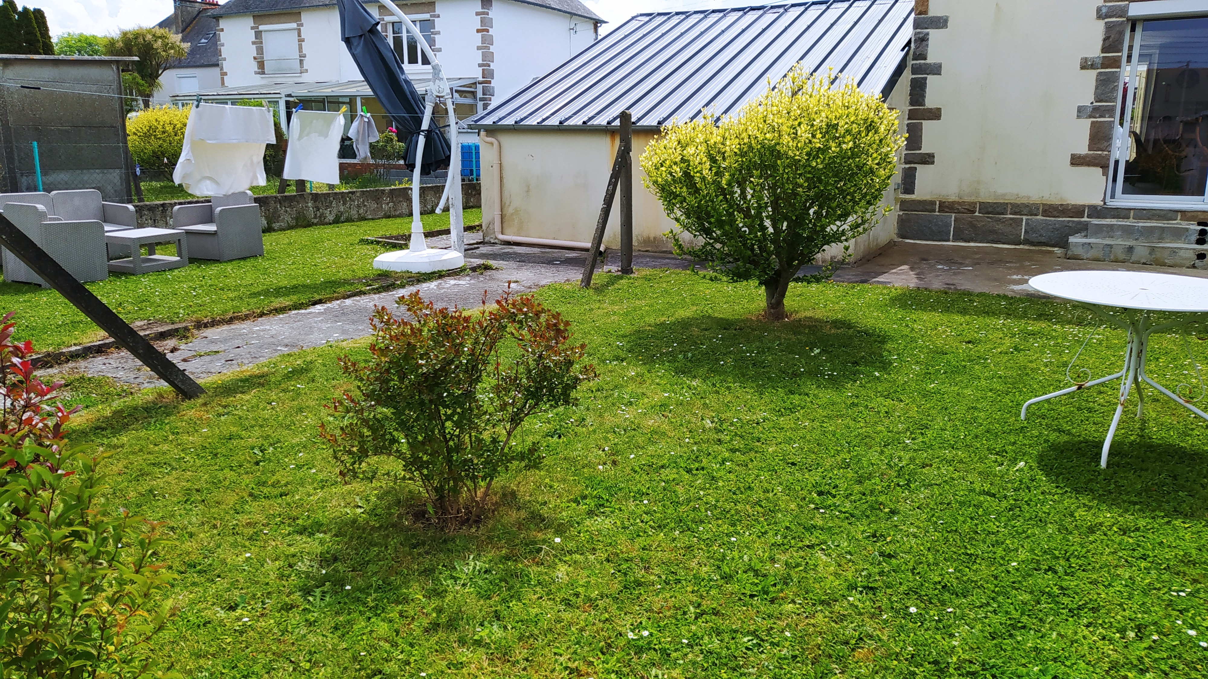 Jardin à l'arrière de la maison avec pelouse, terrasse, 2 salons de jardins haut et bas et parasol. Garage fermé pour stocker vos vélos, poussettes, paddle, etc.
