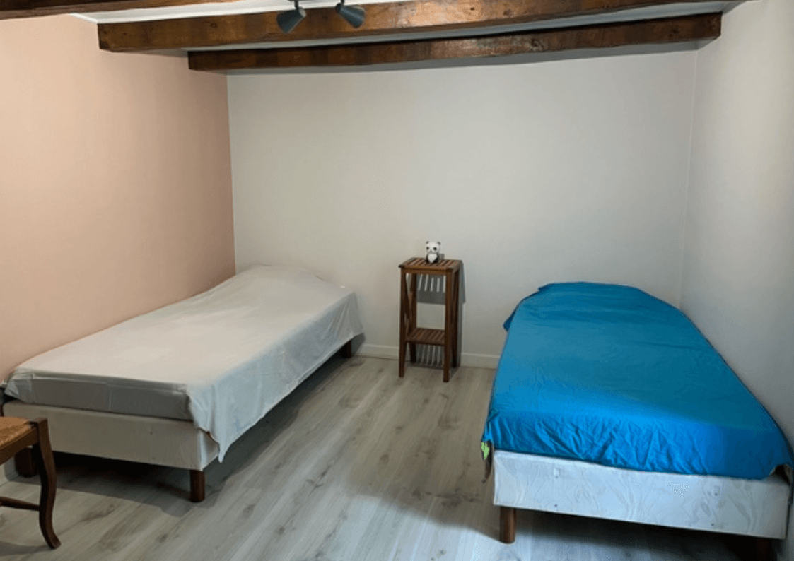 Chambre grise  avec deux lits doubles et meubles d’époque dans une demeure de charme