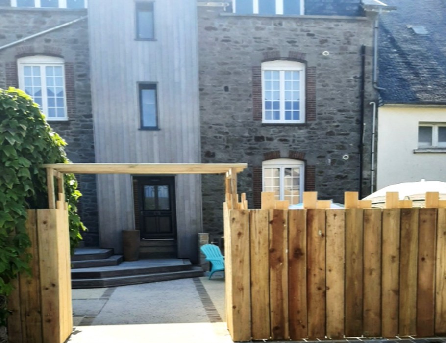 Façade arrière de la bâtisse, avec une agréable terrasse ensoleillée propice à des moments de convivialité avec les autres vacanciers.
