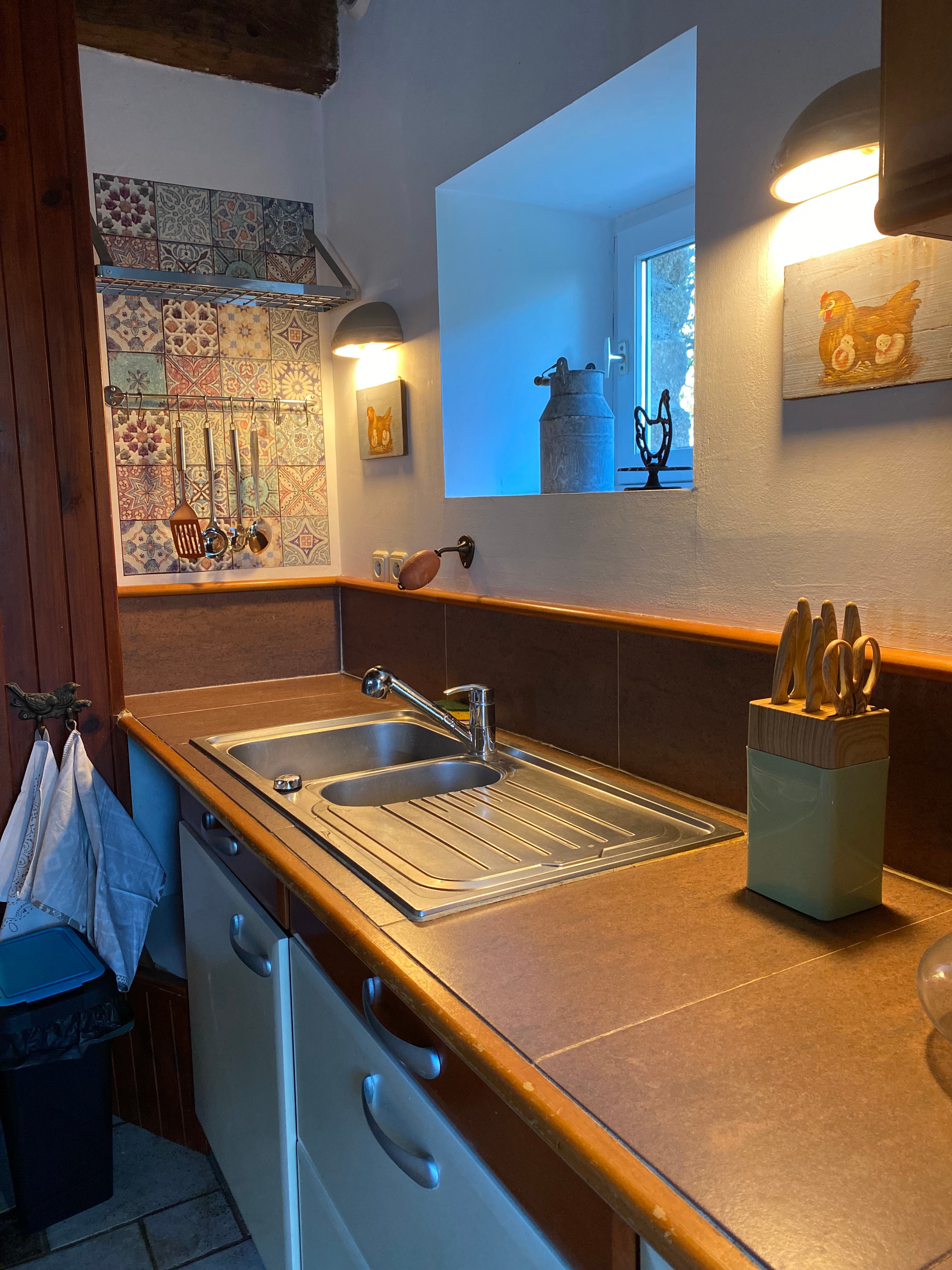 Grande pièce de vie au rez-de-chaussée avec espace cuisine toute aménagée et son mini bar, espace séjour, espace (vrai) bureau, et espace salon avec canapé en cuir, poêle à bois et TV.