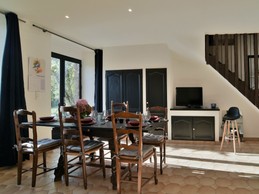 Grande pièce de vie au RDC avec coin cuisine ouverte, toute équipée et comptoir, coin salon avec cheminée, coin séjour.