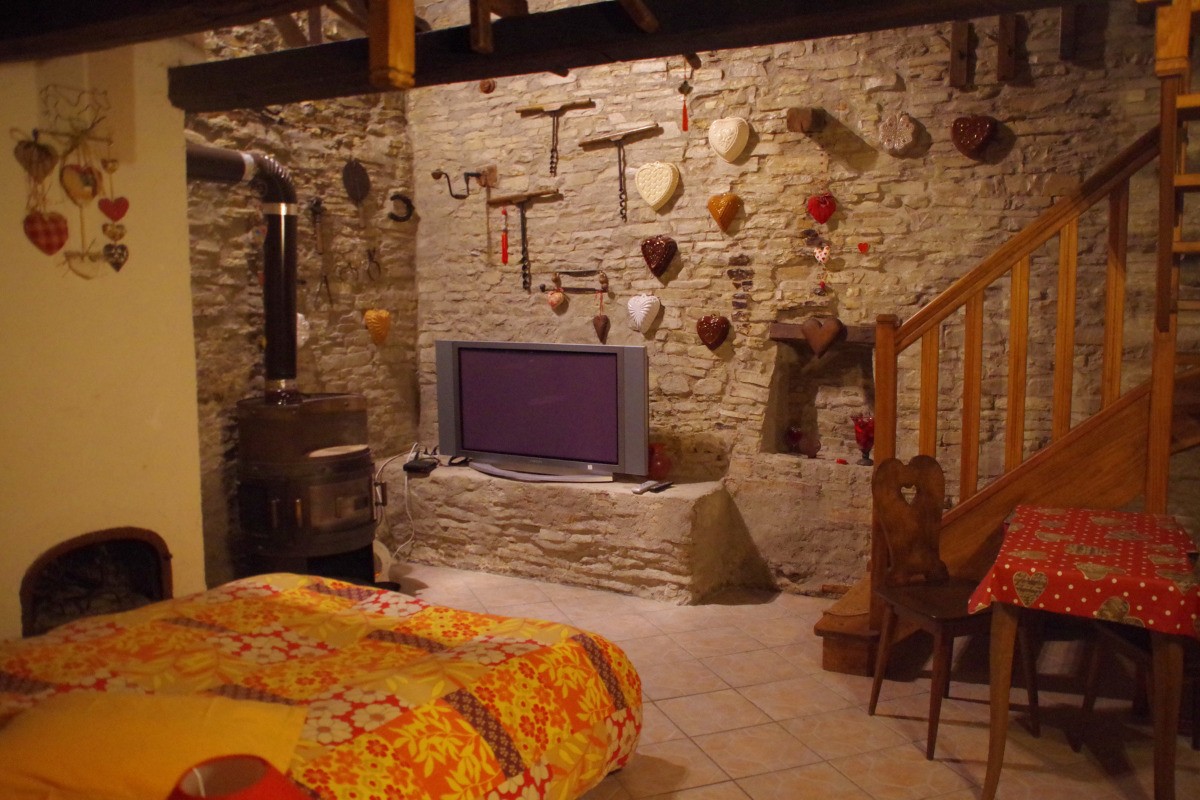 La partie plain-pied accueille un grand lit et un coin salon, équipé d'un téléviseur grand écran plat, au coin du poêle à bois.