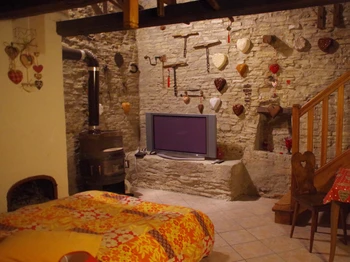 La partie plain-pied accueille un grand lit et un coin salon, équipé d'un téléviseur grand écran plat, au coin du poêle à bois.