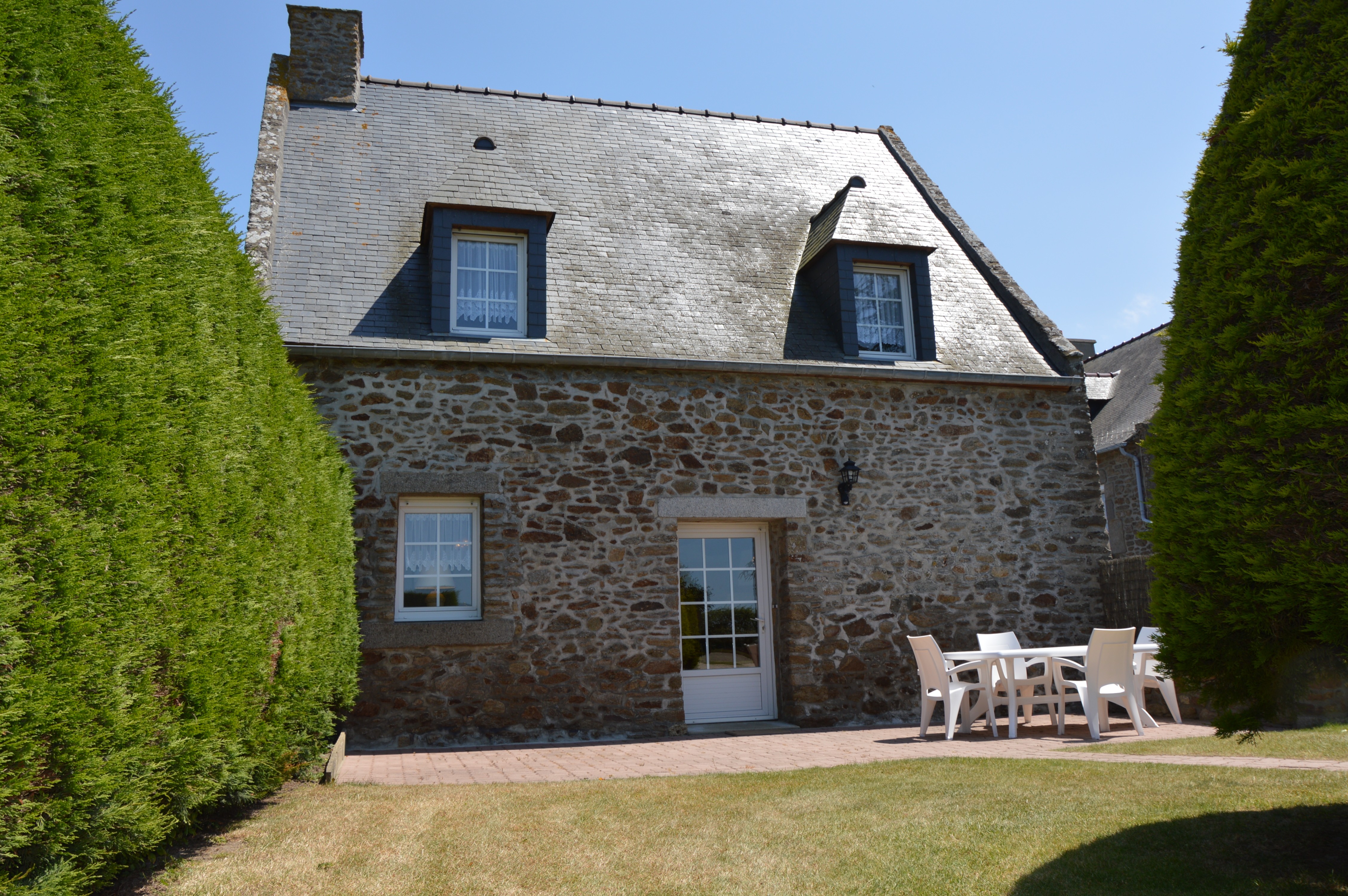 Agréable jardin de 600 m² avec terrasse et salon de jardin, transats, et barbecue.