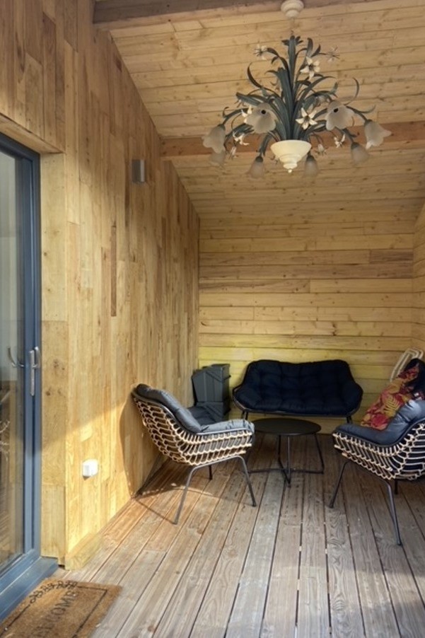 Grande terrasse de plus de 40 mètres carrés avec transats et salon de jardin.  Ici la partie abritée.