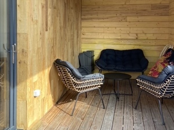 Grande terrasse de plus de 40 mètres carrés avec transats et salon de jardin. Ici la partie abritée.