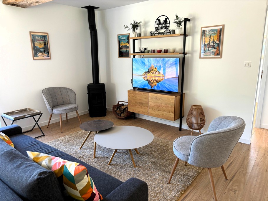 Grande pièce de vie avec salon (poêle à bois, smart TV), séjour et cuisine ouverte parfaitement équipée.