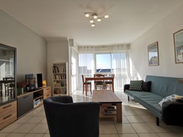 Pièce de vie avec salon, table et cuisine équipée aménagée