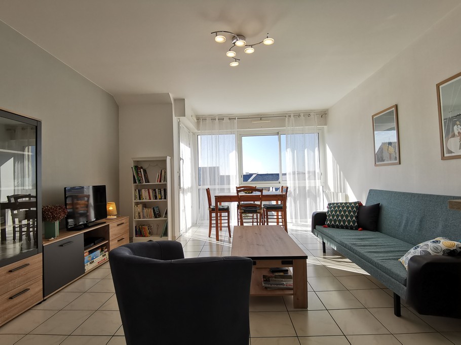 Pièce de vie avec salon, table et cuisine équipée aménagée