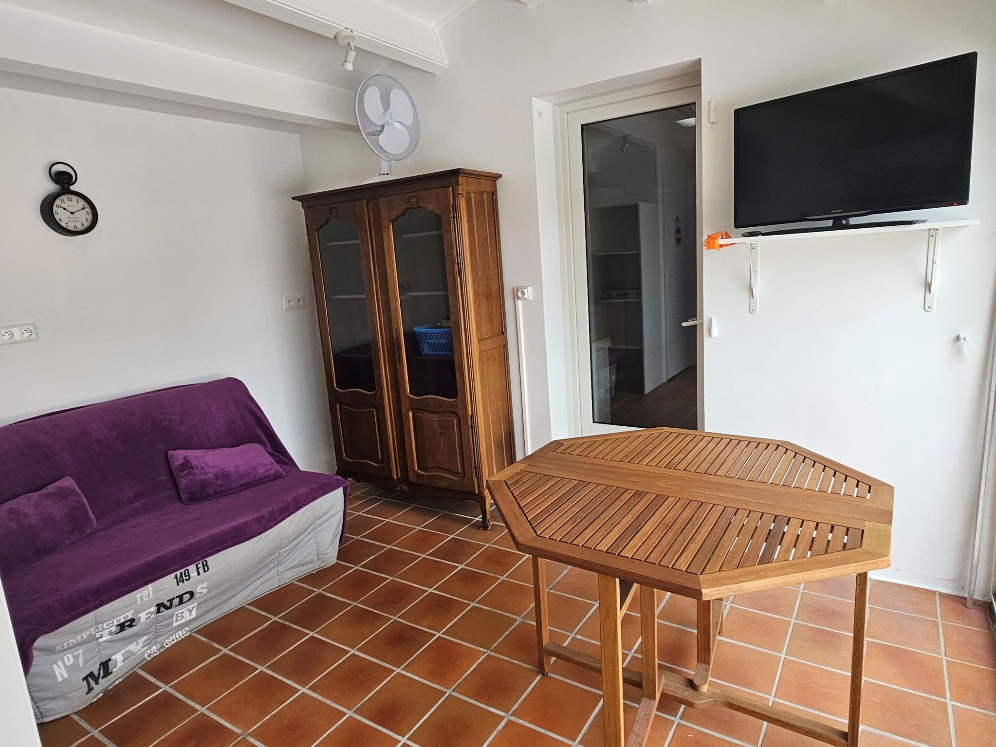 Piece vitrée donnant accès à la terrasse, coin avec télévision et canapé