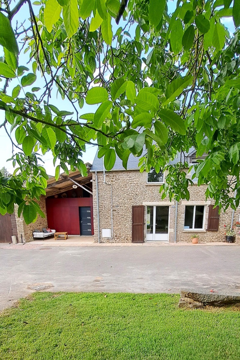 Façade la maison avec à sa gauche une agréable seconde terrasse couverte. 
Petit jardin ombragé au premier plan.