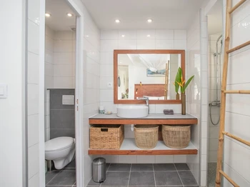 Salle d'eau avec douche à l'italienne et WC fermé.