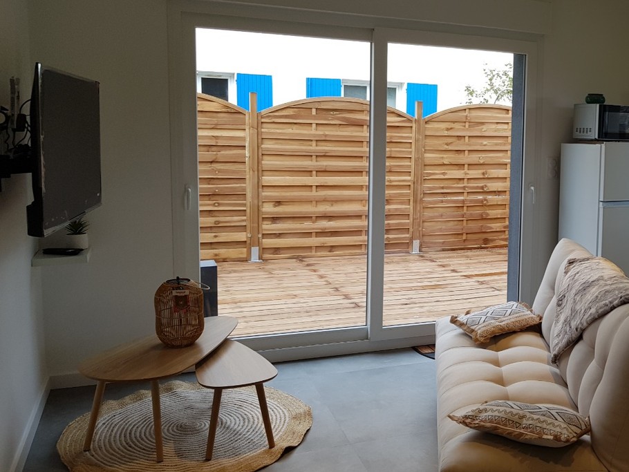 Pièce de vie au rez-de-chaussée avec coin salon avec TV, et coin cuisine et sa table à manger. Canapé convertible pour 2 personnes. Terrasse en bois accessible par un portillon ou par la baie vitrée.