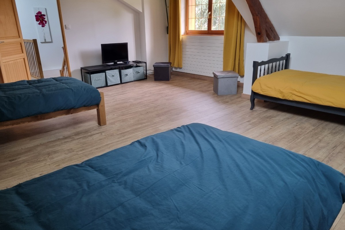 Grande chambre de 3 lits individuels aux couleurs vives et décorée par les enfants