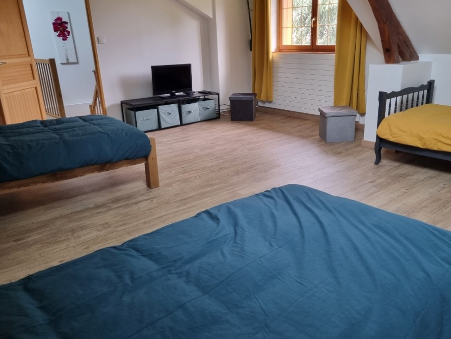 Grande chambre de 3 lits individuels aux couleurs vives et décorée par les enfants