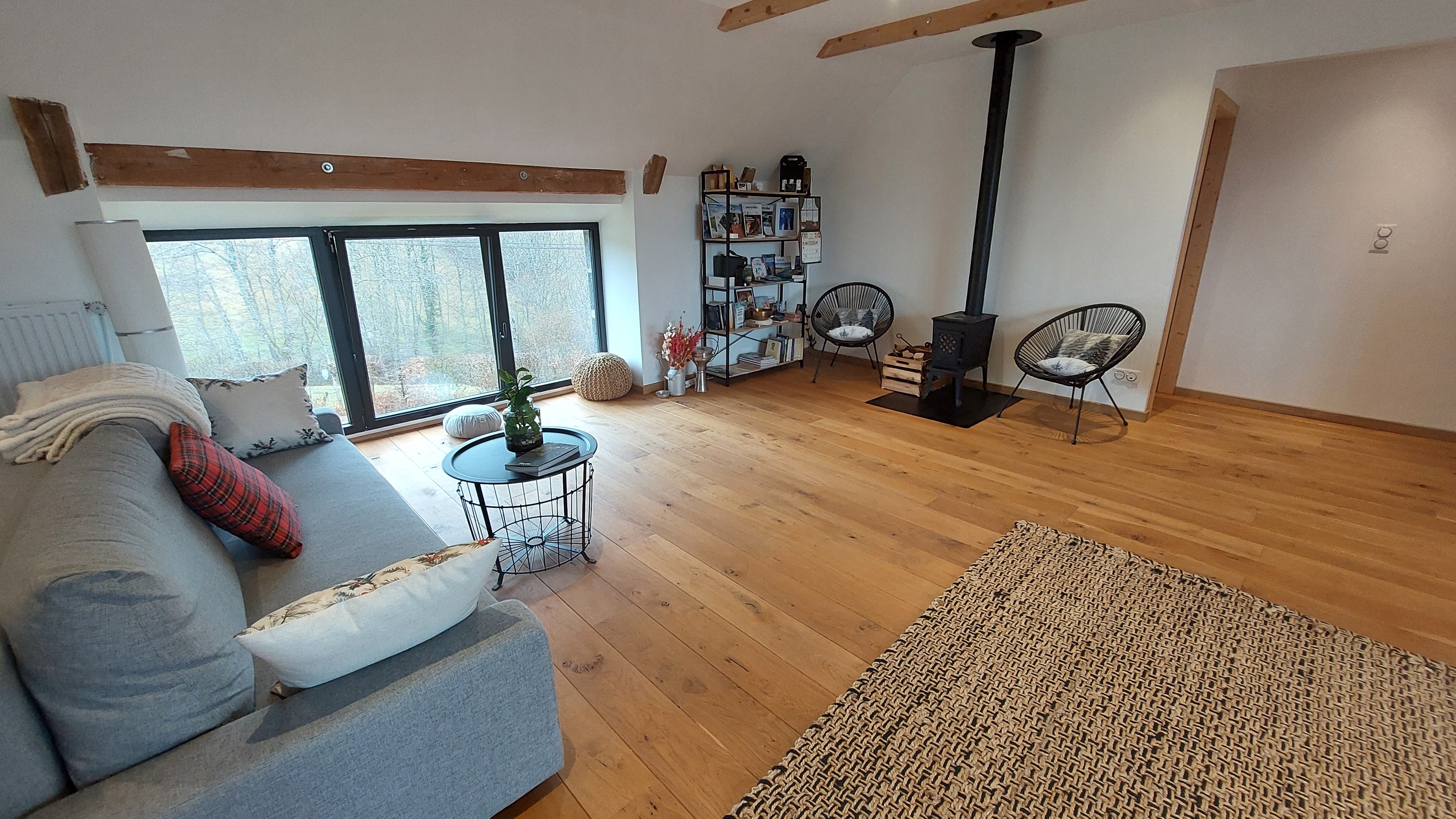 Relaxation area with wood-burning stove and cosy armchairs in a guest house in Marchastel