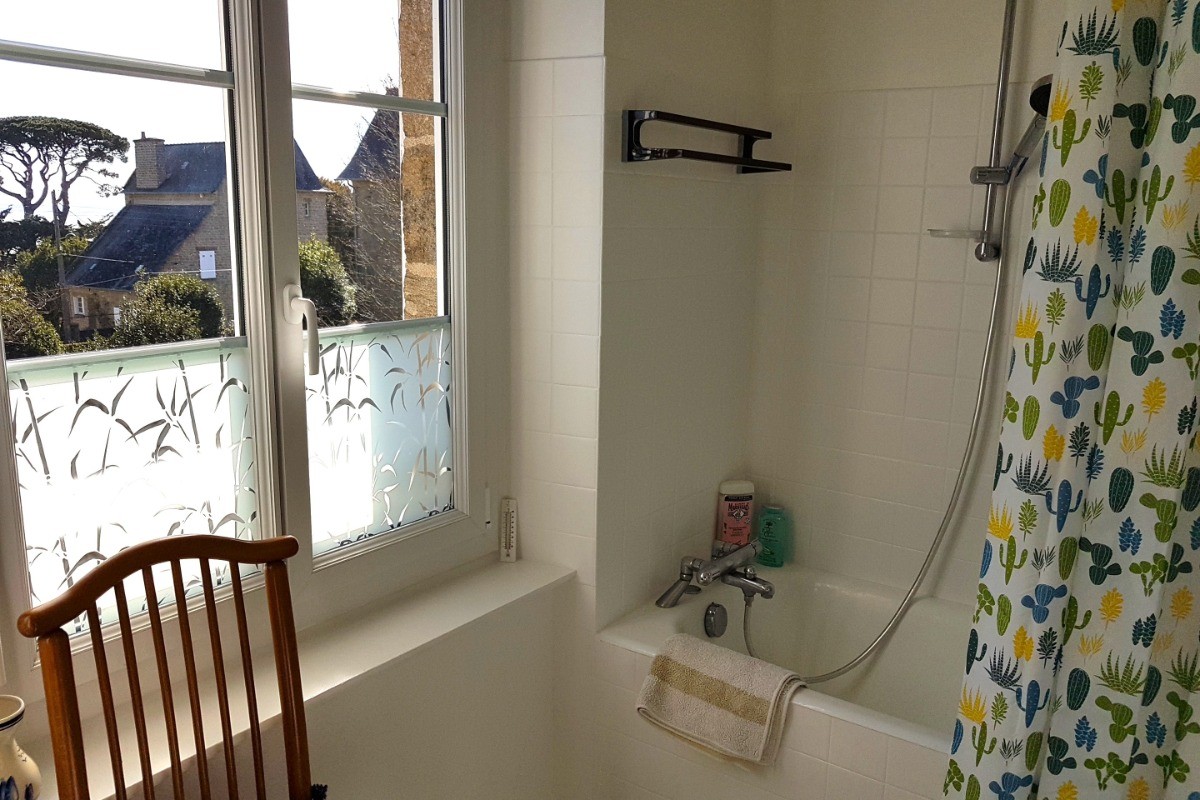 Salle de bain avec baignoire et meuble vasque. Vue mer.