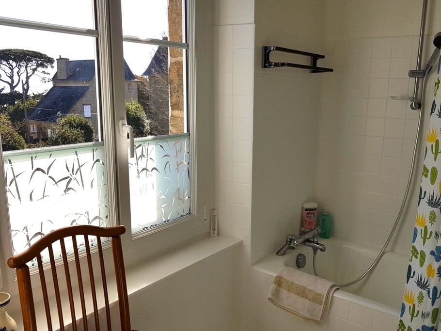 Salle de bain avec baignoire et meuble vasque. Vue mer.