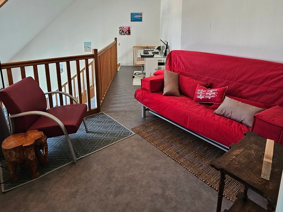 Mezzanine ouverte sur la pièce de vie, avec coin bureau et espace détente avec canapé convertible.