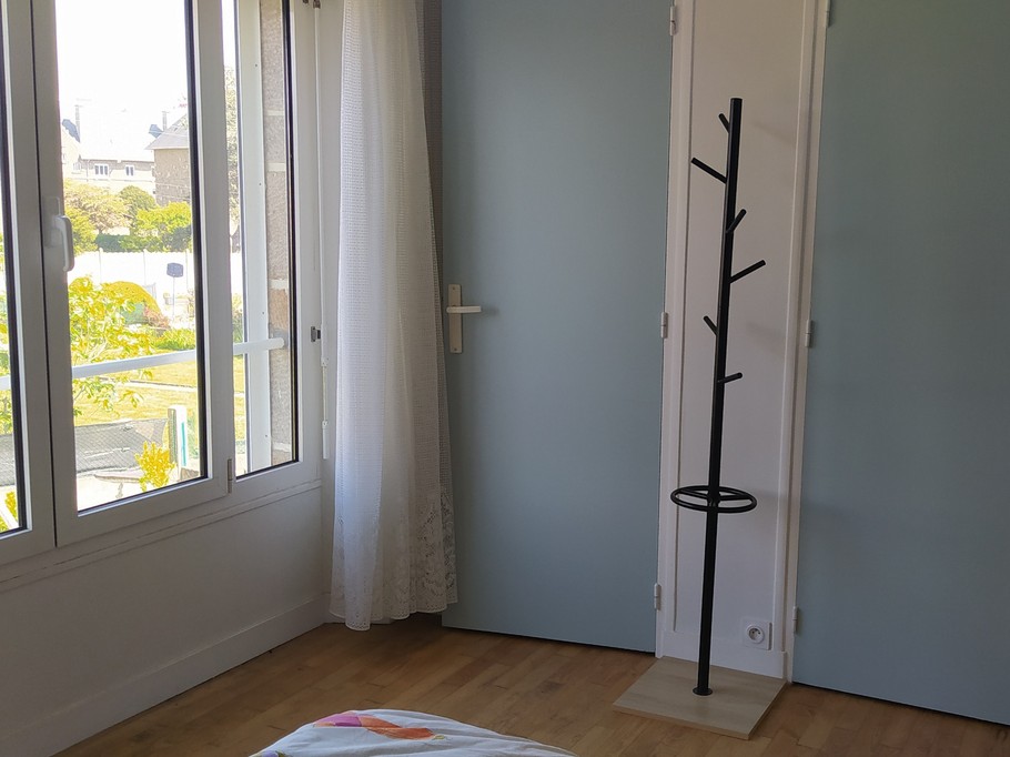 Chambre 1 avec un lit 140 cm, rangements, porte-manteau, et salle d'eau communicante (douche grande dimension et meuble vasque avec miroir)