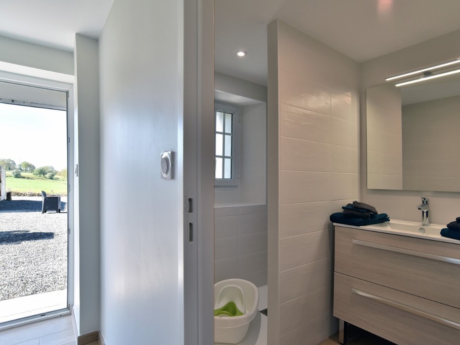 Salle d'eau avec douche à l'italienne spacieuse, meuble vasque et radiateur sèche serviette.