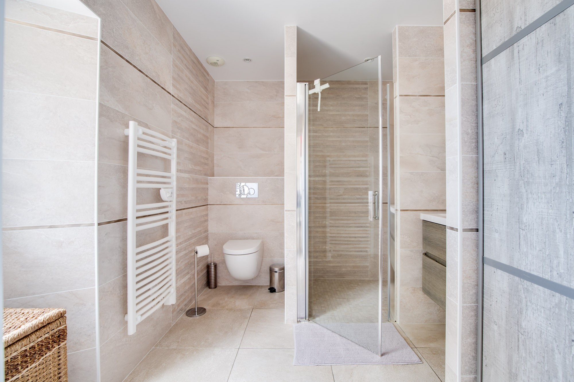 Salle de bain avec douche italienne, colonne de douche hydromassante et WC.