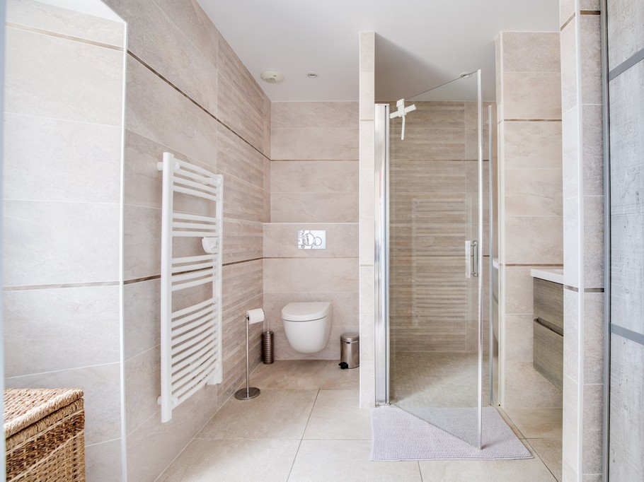 Salle de bain avec douche italienne, colonne de douche hydromassante et WC.