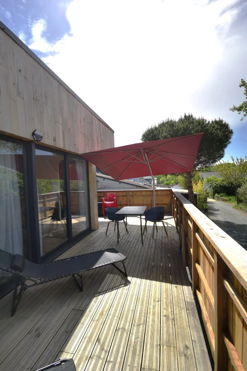 Grande terrasse de plus de 40 mètres carrés avec transats et salon de jardin.