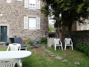 Espace repas extérieur avec coussins, barbecue, parasol à disposition.