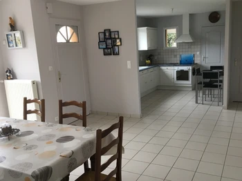 Grande pièce de vie avec cuisine aménagée moderne.