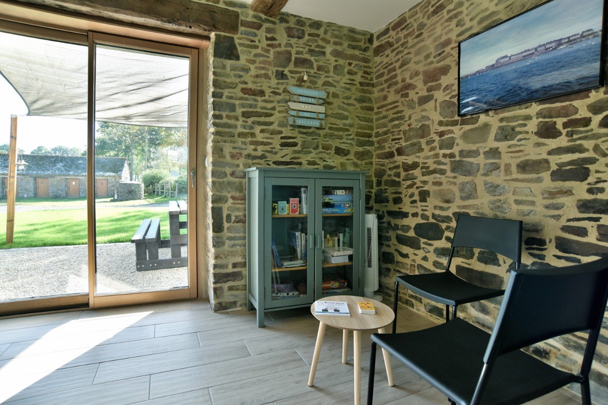 Grande pièce de vie avec poutres apparentes. Coin jeu / lecture. Vue sur la cour, la terrasse et la pelouse en rez-de-jardin.