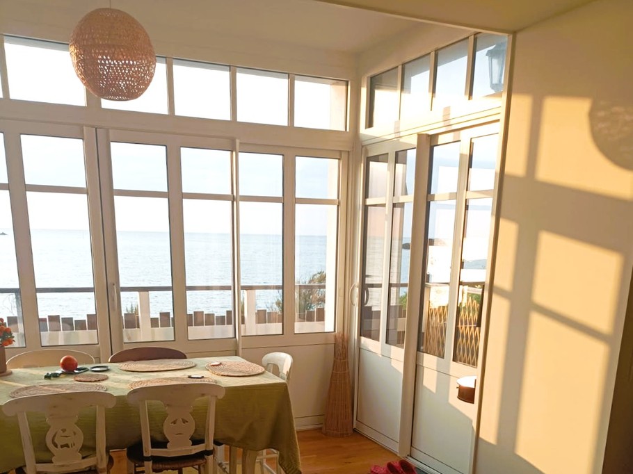 Grande pièce de vie avec 2 salons, un poêle à bois, un séjour dans la véranda vue mer.