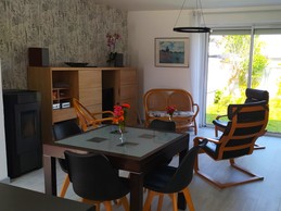 Pièce de vie au RDC avec entrée, cuisine, séjour, salon et poêle à bois.