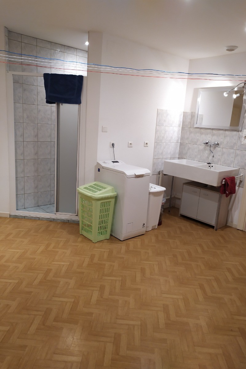 Lingerie avec machine à laver, sèche linge, lavabo et une douche.
