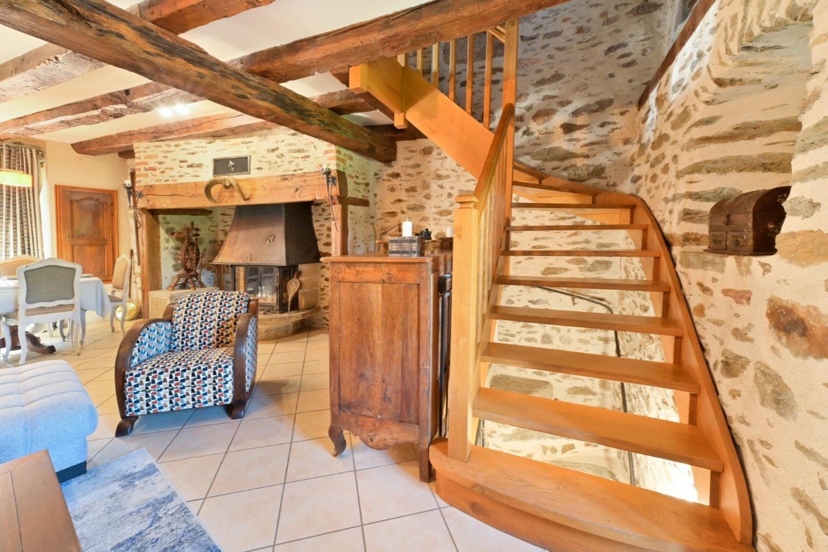 Escalier en bois élégant menant à l'étage du gîte de Leynhac, mêlant charme rustique et authenticité