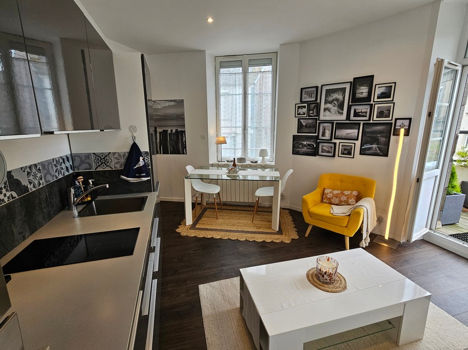 Pièce de vie joliment décorée, cuisine très bien équipée. Accès direct à la terrasse en bois.