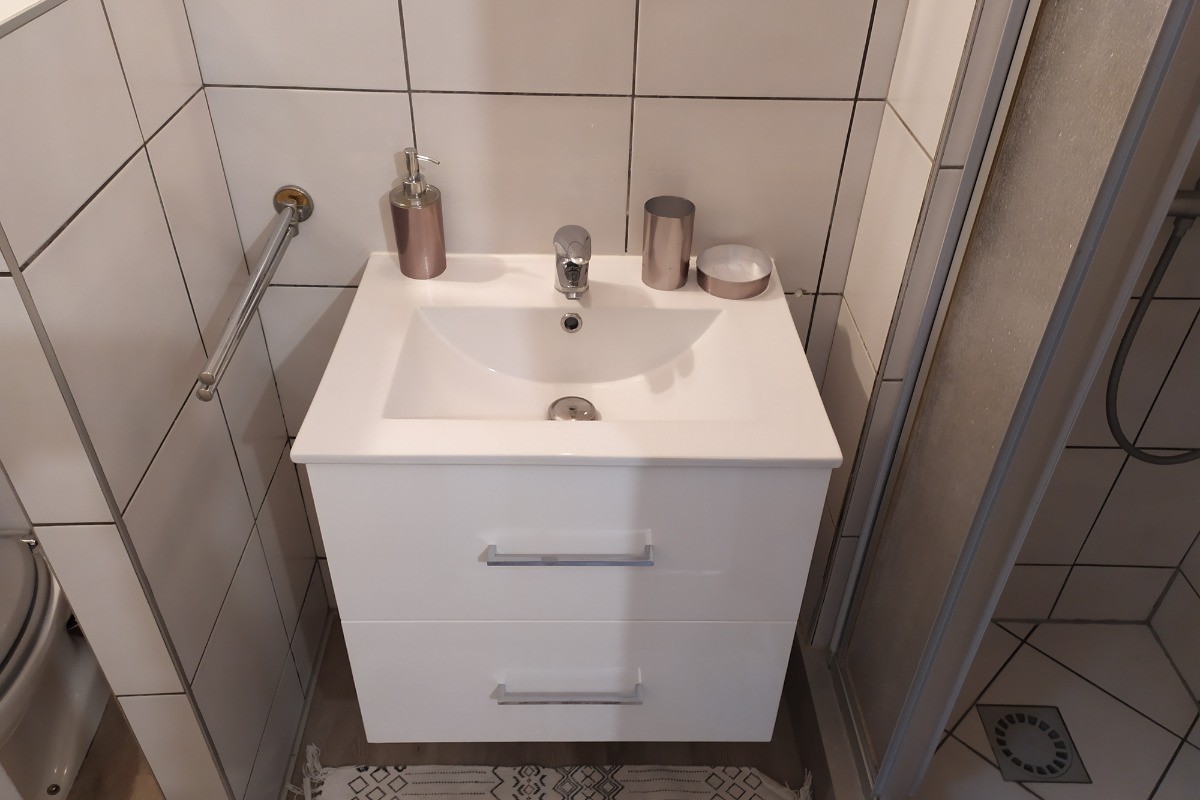Salle d'eau avec wc, lavabo sèche serviettes et cabine de douche.