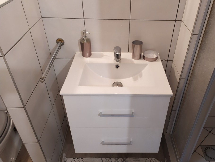 Salle d'eau avec wc, lavabo sèche serviettes et cabine de douche.