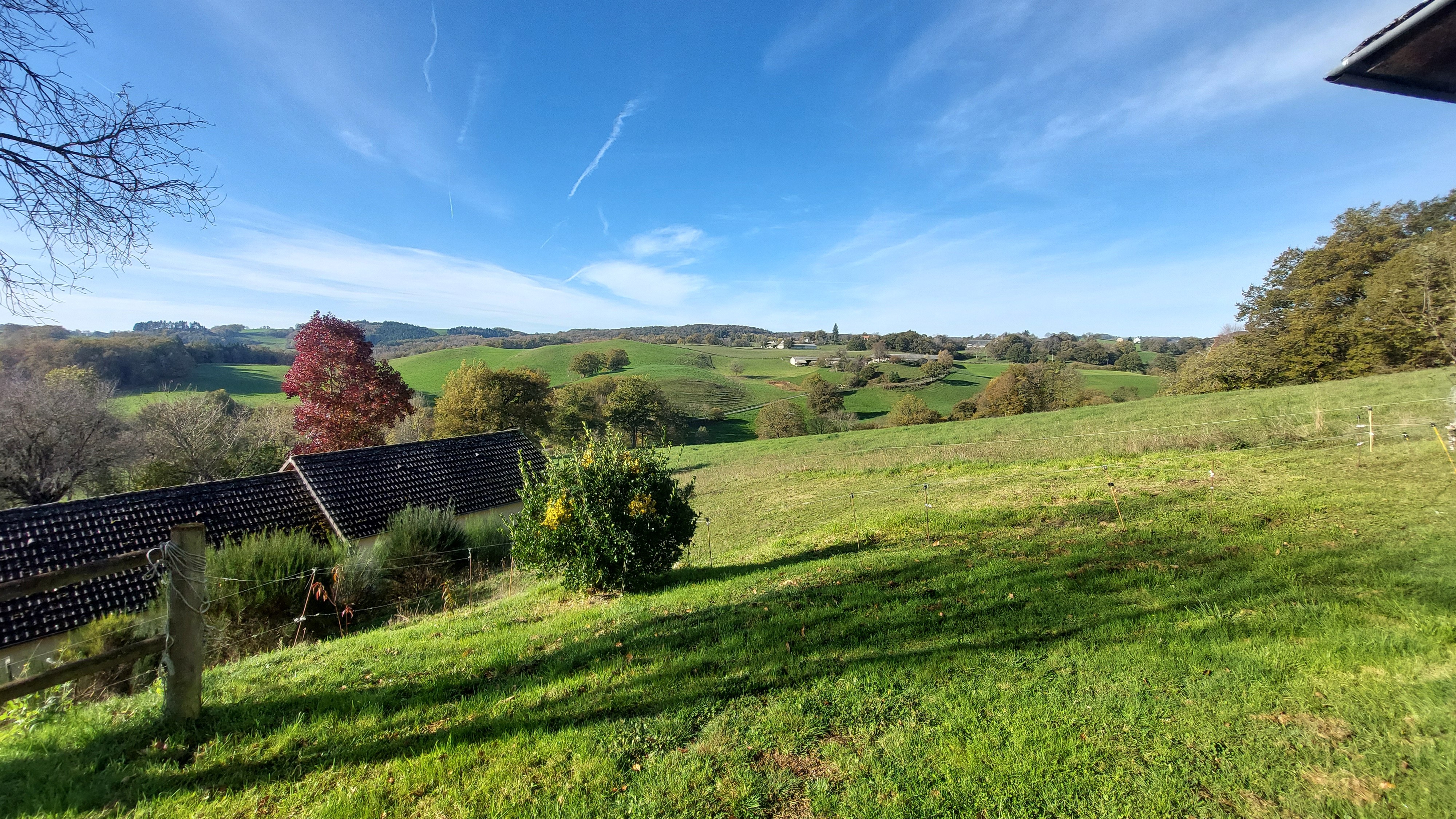 Extérieur du gîte avec jardin et vue panoramique sur la campagne.